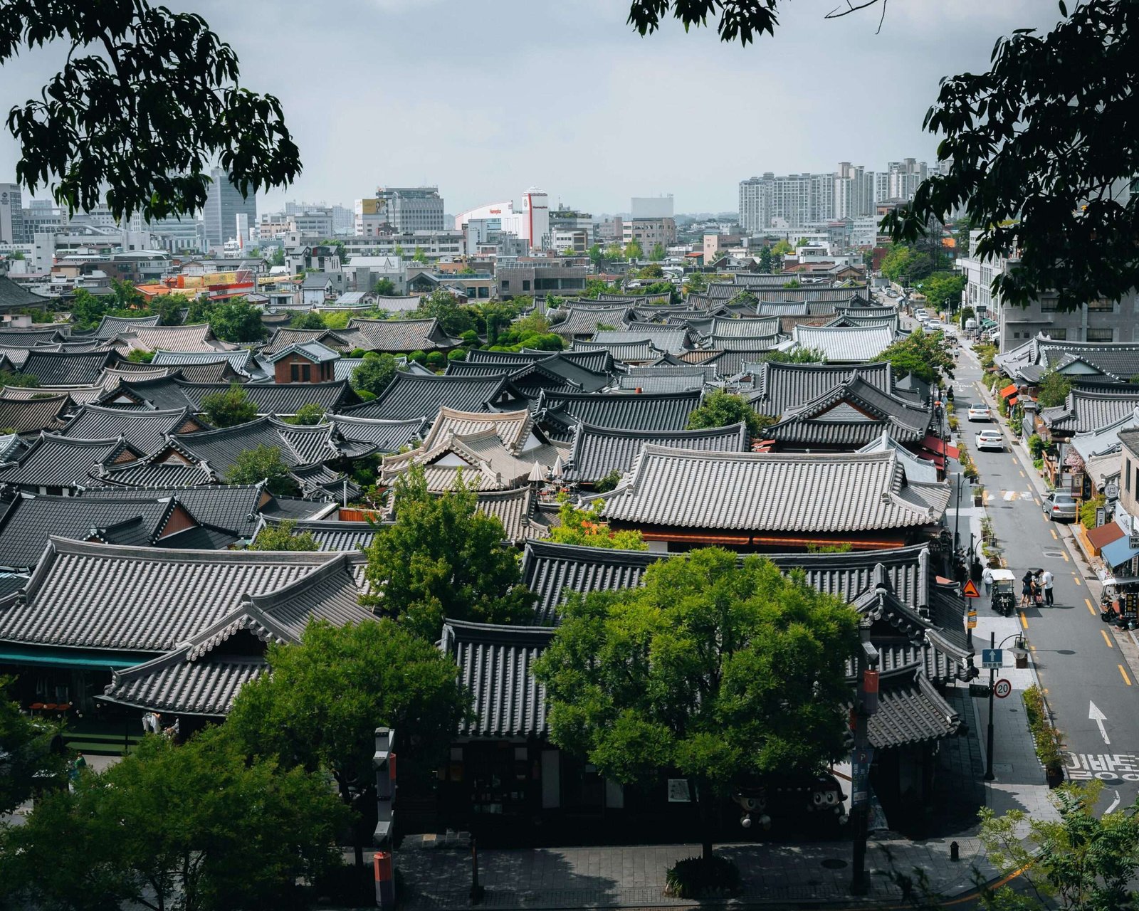 pexels-photo-13885524-13885524 Aerial view of traditional rooftops in Jeonju Hanok Village, South Korea with city skyline in the background.