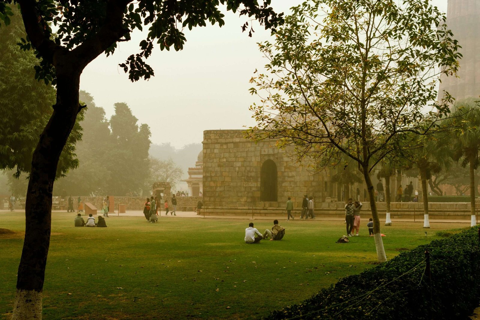 People relaxing at the Qutb Minar park in Delhi, India on a peaceful misty day.