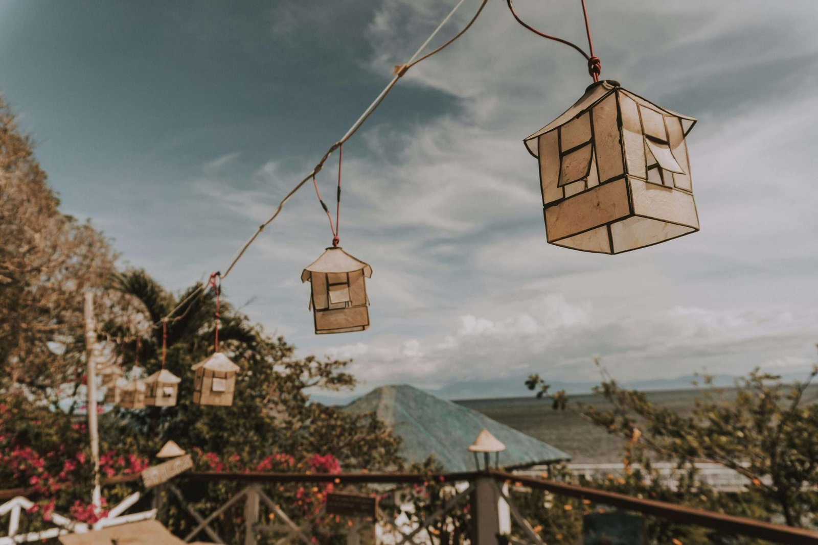 Charming rustic lanterns hanging outdoors with ocean view and clear sky.
