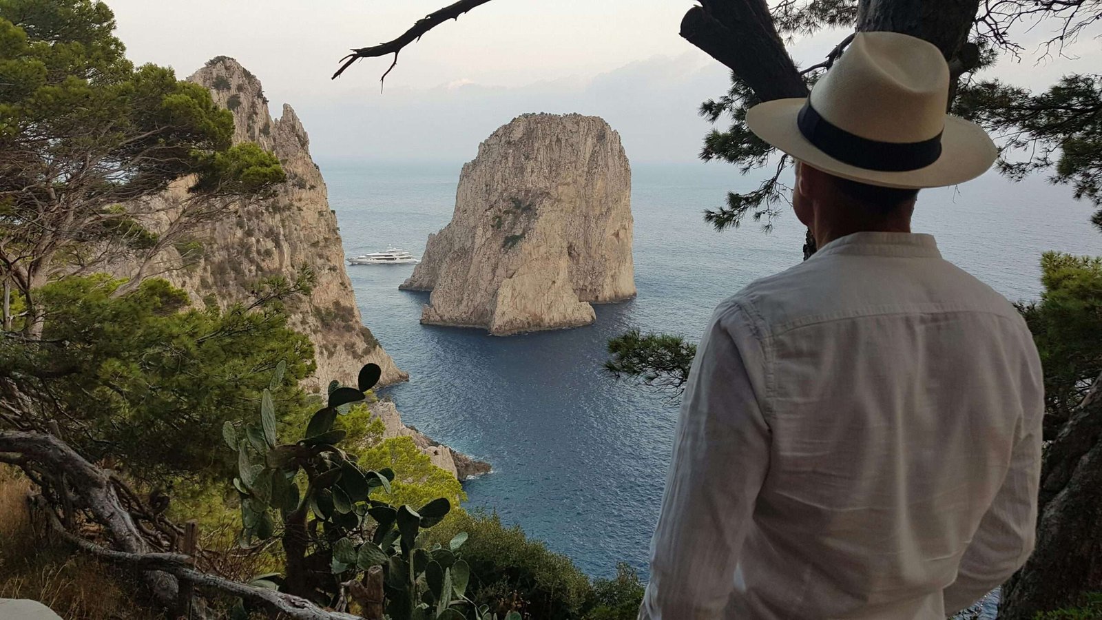 pexels-photo-9905303-9905303 A man with a hat admires the Faraglioni rock formations in Capri, Italy.